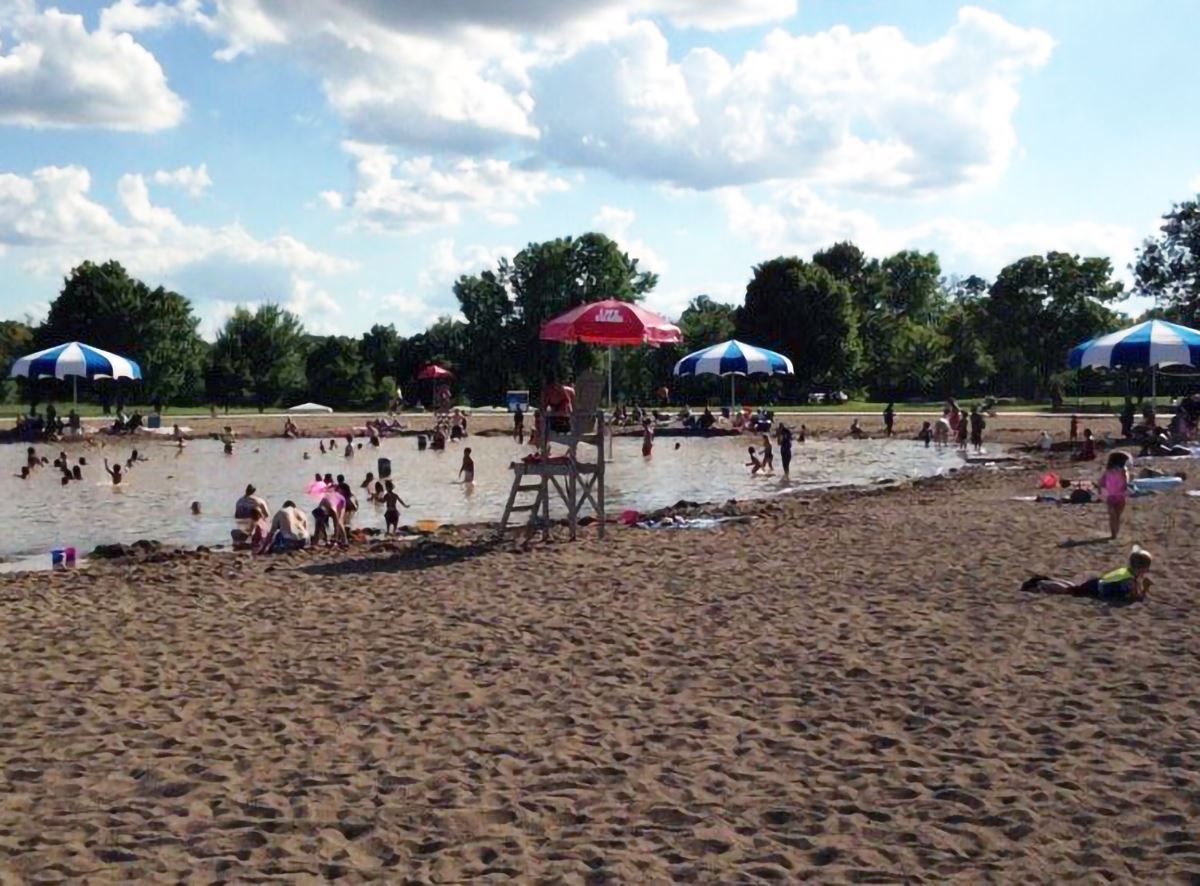 People on the beach and in the water at the Swim Pond in Lake Elmo Park Reserve.