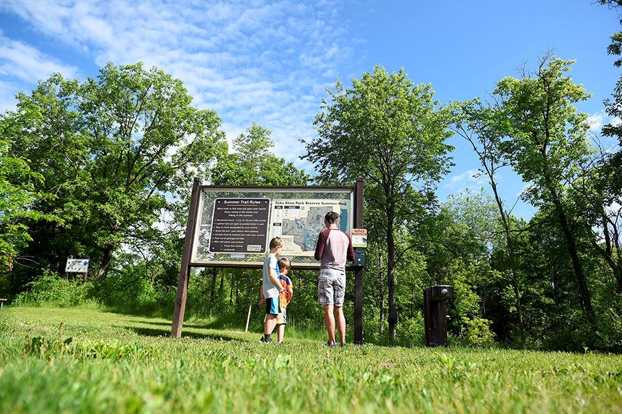 Man and children looking at park map enjoying nature and outdoor