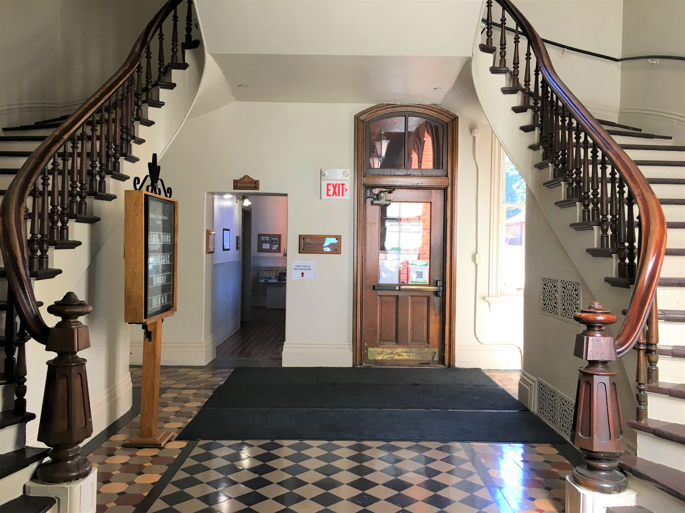 Curved double staircase at the Historic Courthouse with dark wood railings and white walls