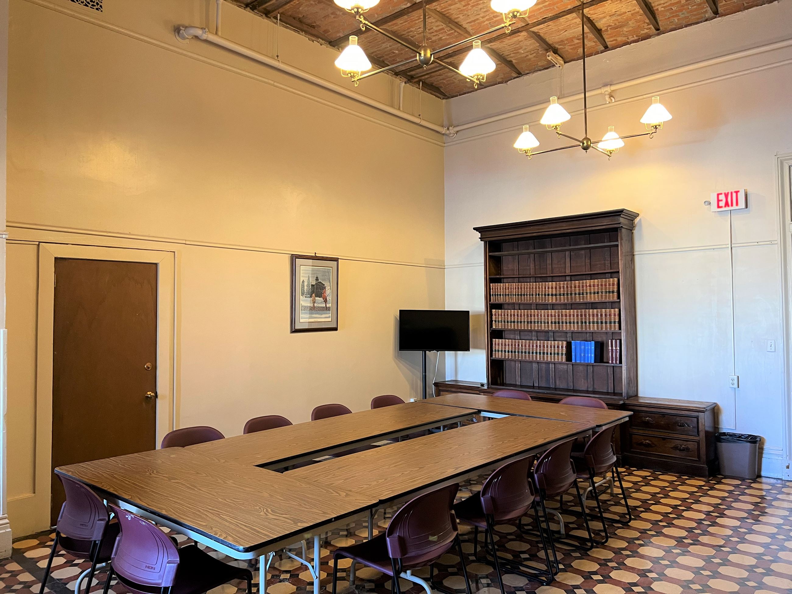 Treasurers Office meeting space with ivory colored walls and an exposed brick ceiling